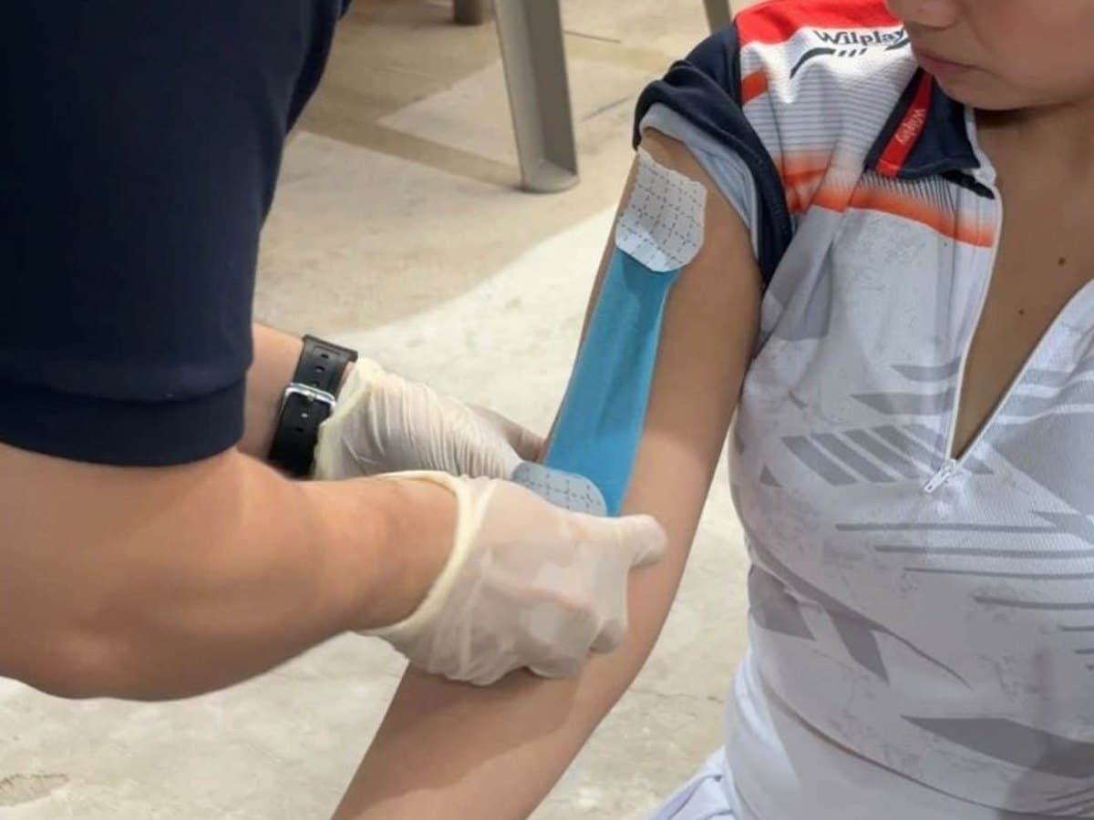 Therapist applying kinesiology tape to a patient's knee