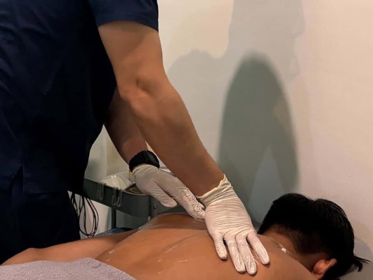 Therapist massaging the upper back of a patient lying face down