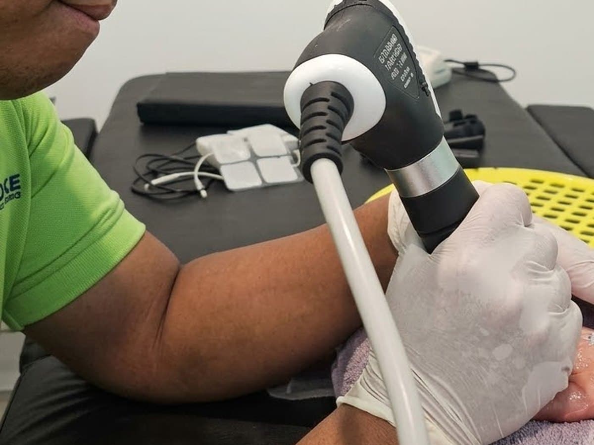Therapist applying a shockwave applicator to the sole of a patient's foot