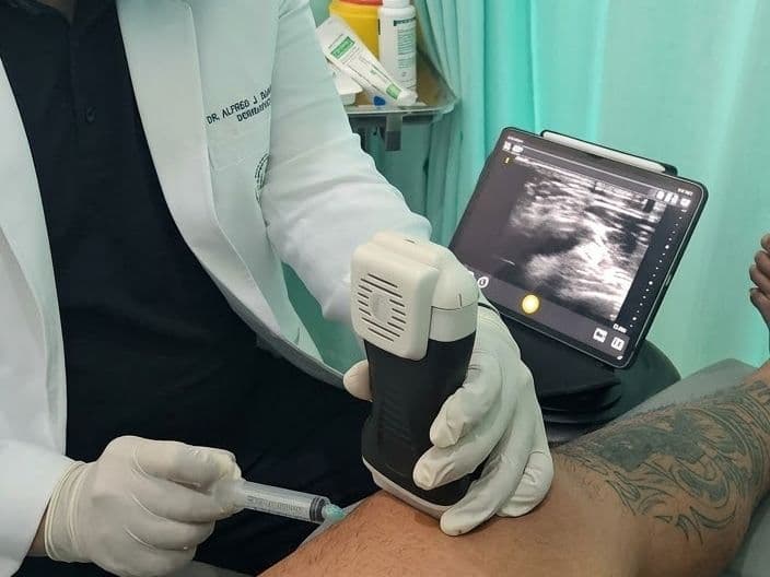 Doctor giving an ultrasound-guided injection into a patient's knee