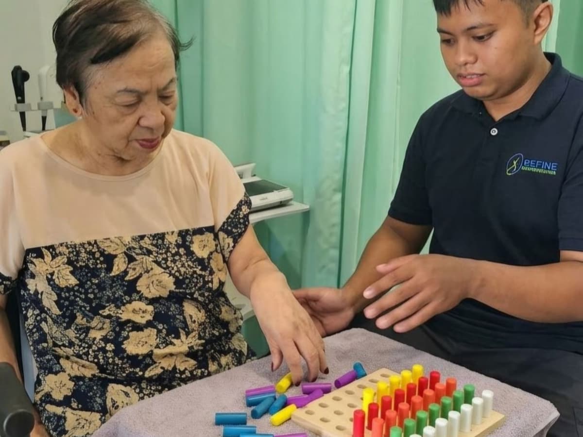 Therapist guiding a patient through a hand exercise on a colored peg board